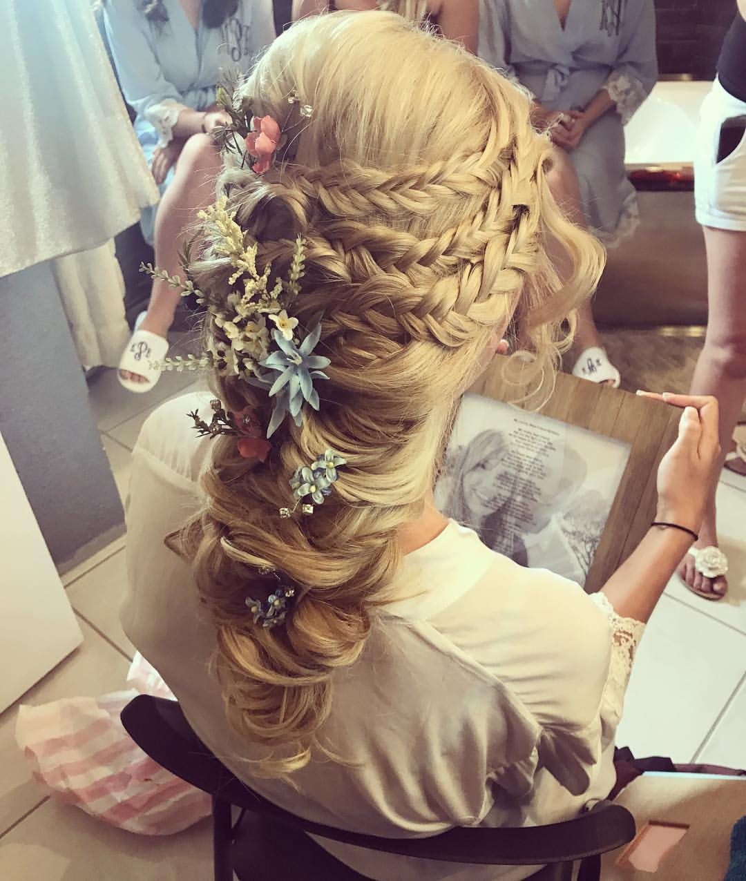 Bride from above with a full braided side style tucked with tiny blue and coral flowers